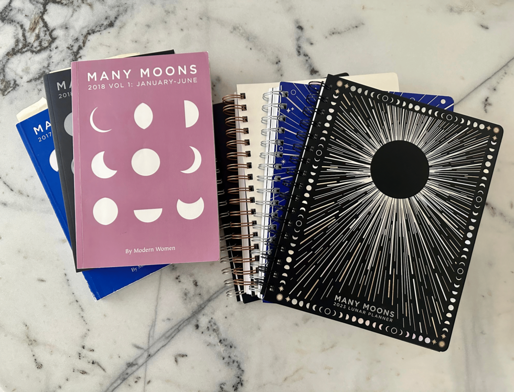 Copies of my Many Moons planners by Moon Studio on a marble table. Here are magical tools to change consciousness at will.